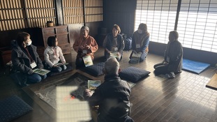 囲炉裏を囲んで説明を受ける参加者